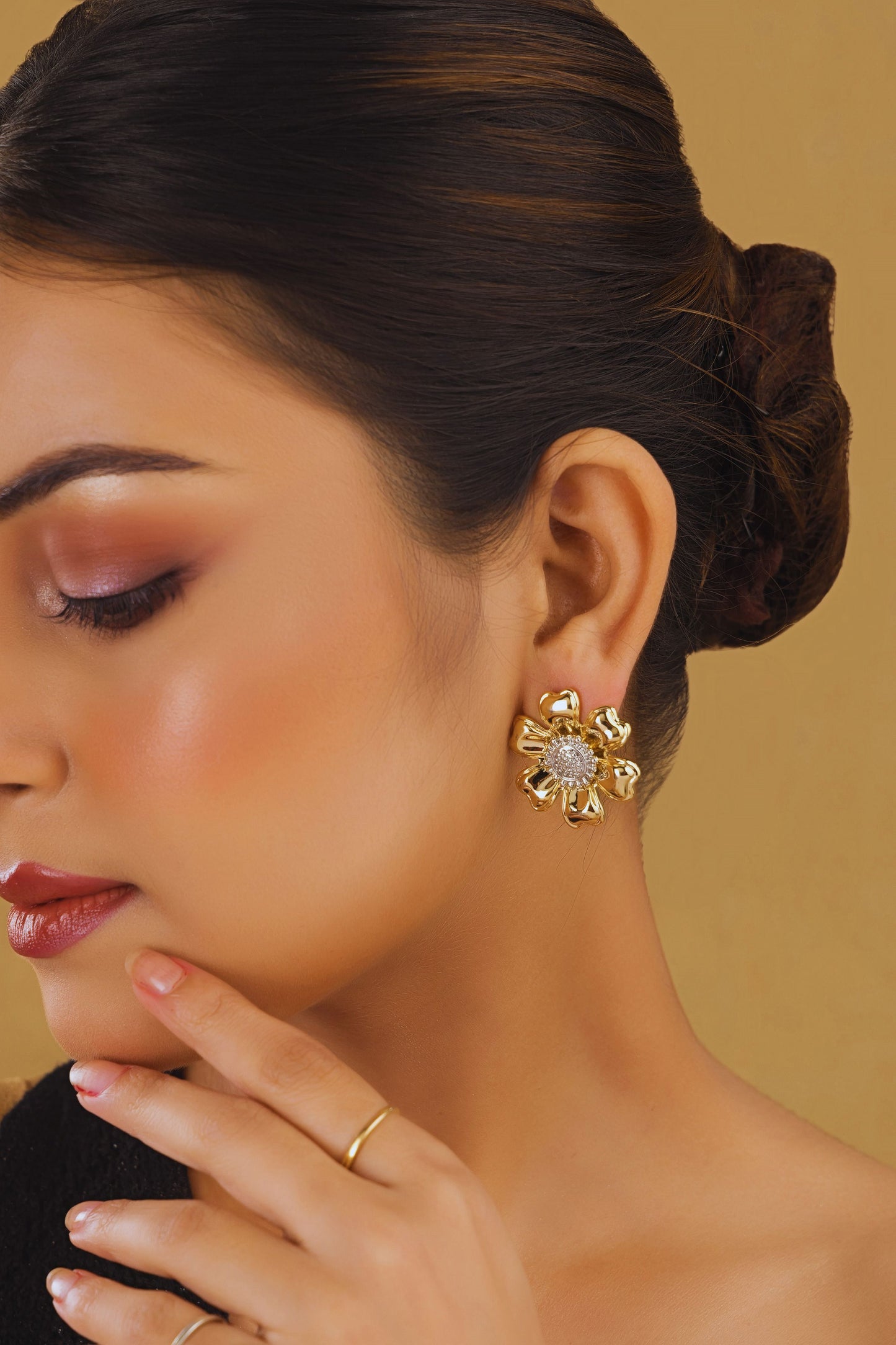 Close-up of a woman wearing gold earrings with a beige background