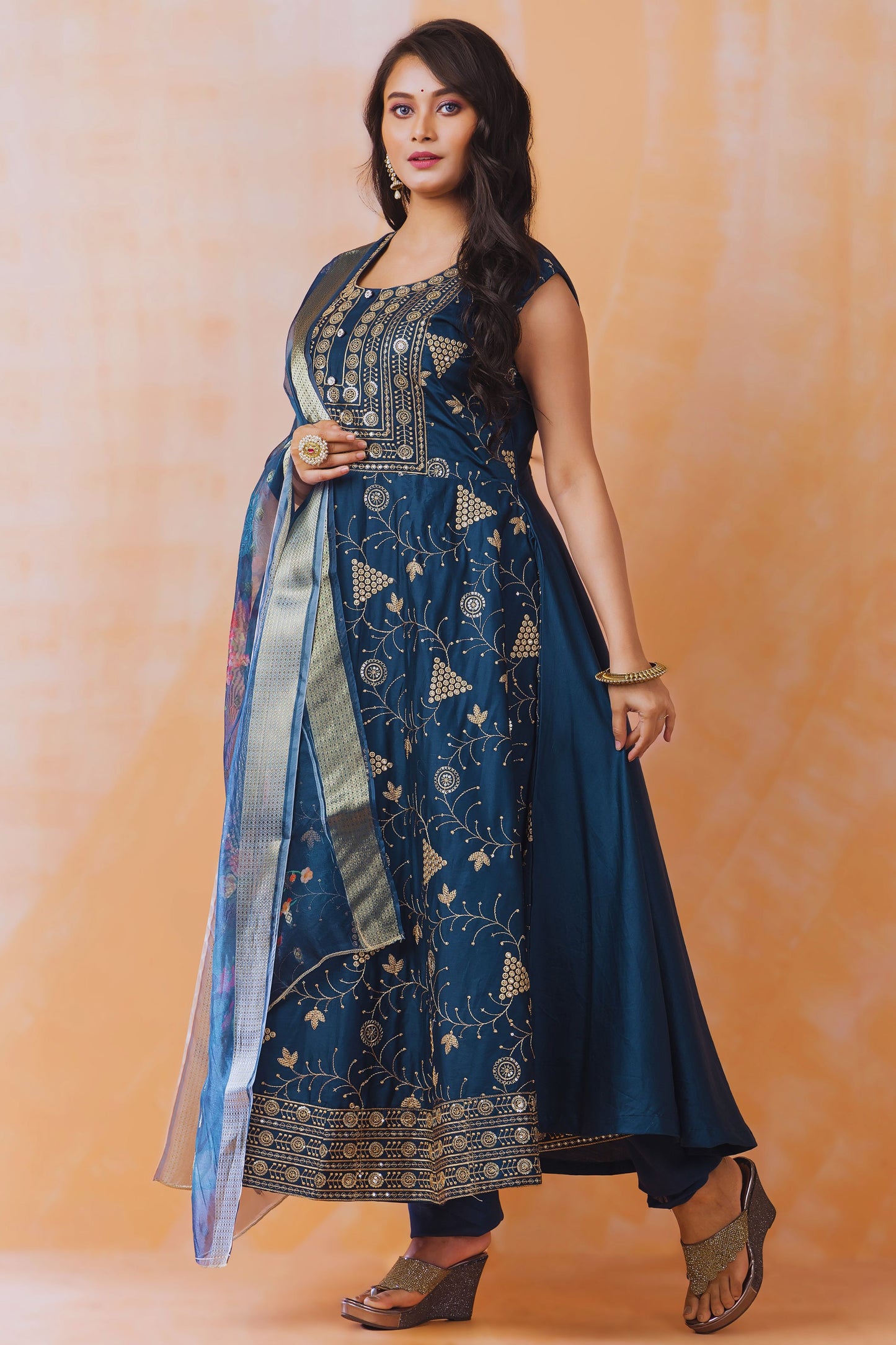 Woman wearing a blue embroidered traditional outfit on an orange background