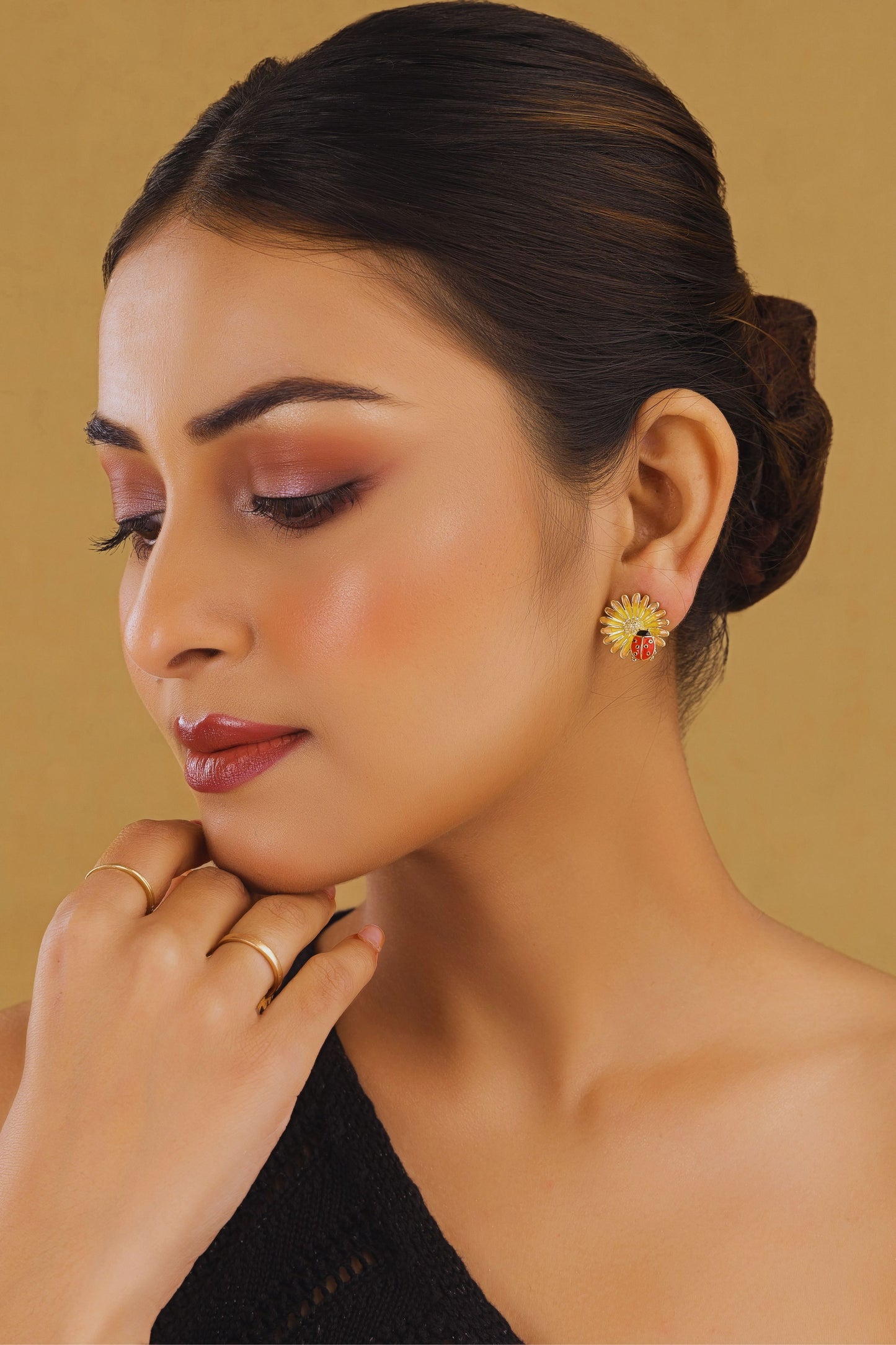 Woman wearing a colorful earring against a beige background