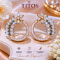 Pair of star-shaped earrings with floral designs on a soft pink background, featuring the TITOS Fashion House brand.