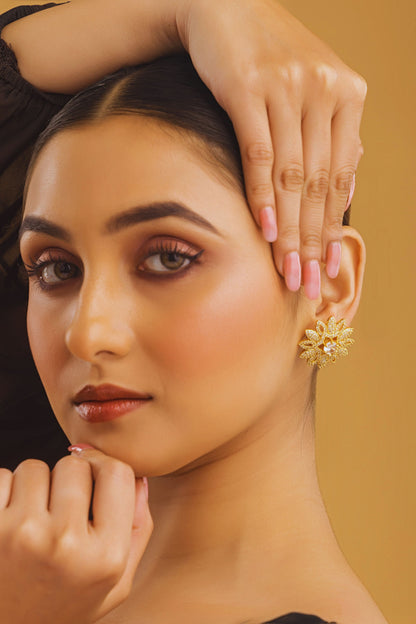 Woman wearing gold earrings with a neutral background