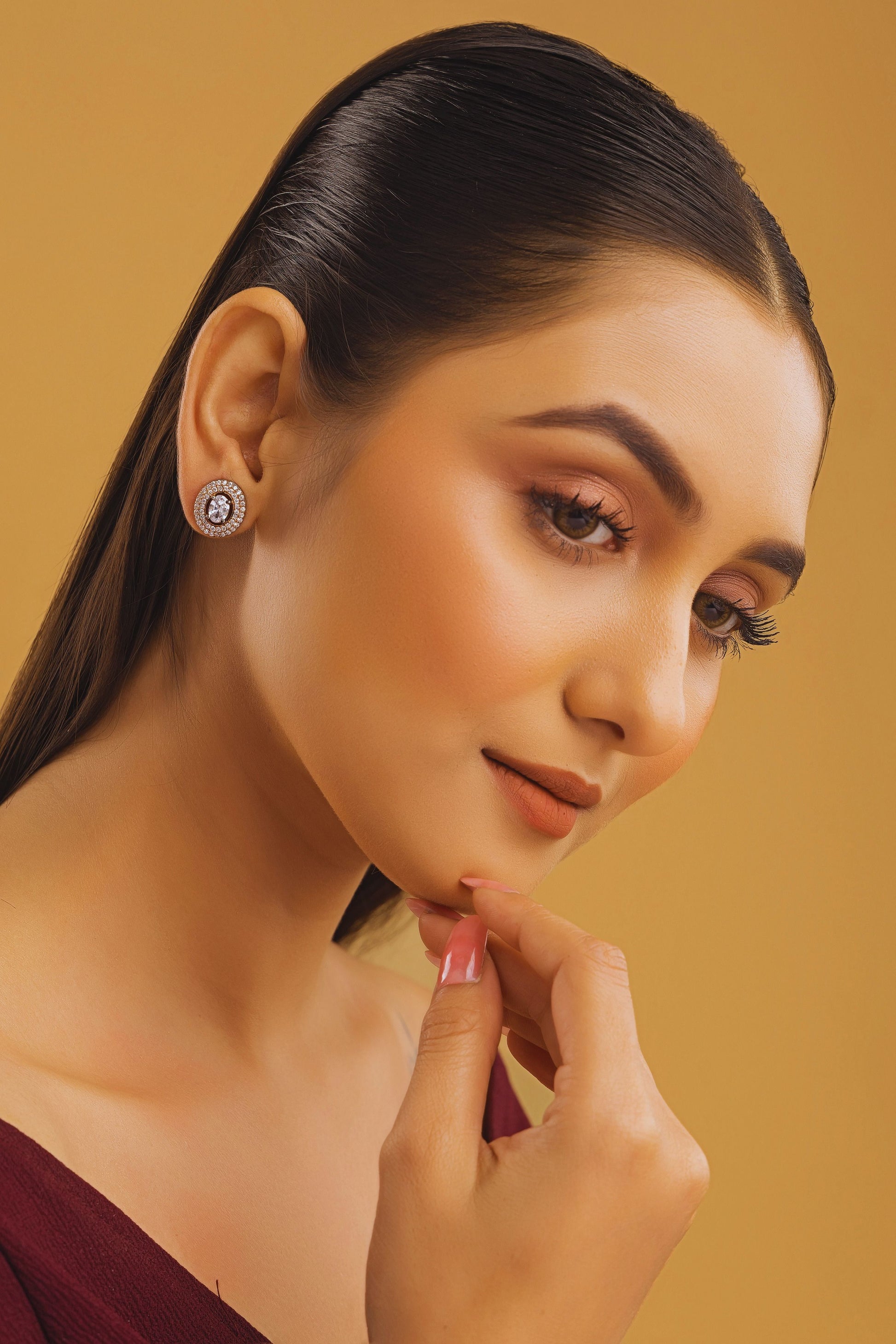Woman wearing earrings with a gold background