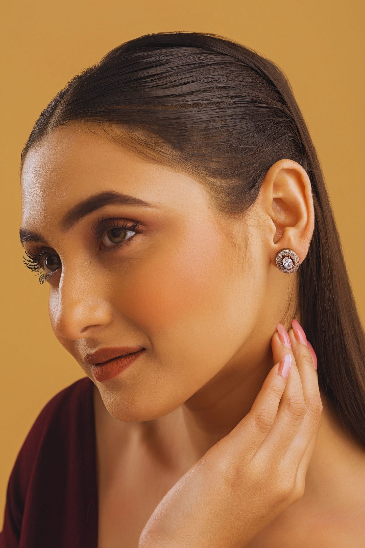 Woman wearing a diamond earring against a beige background