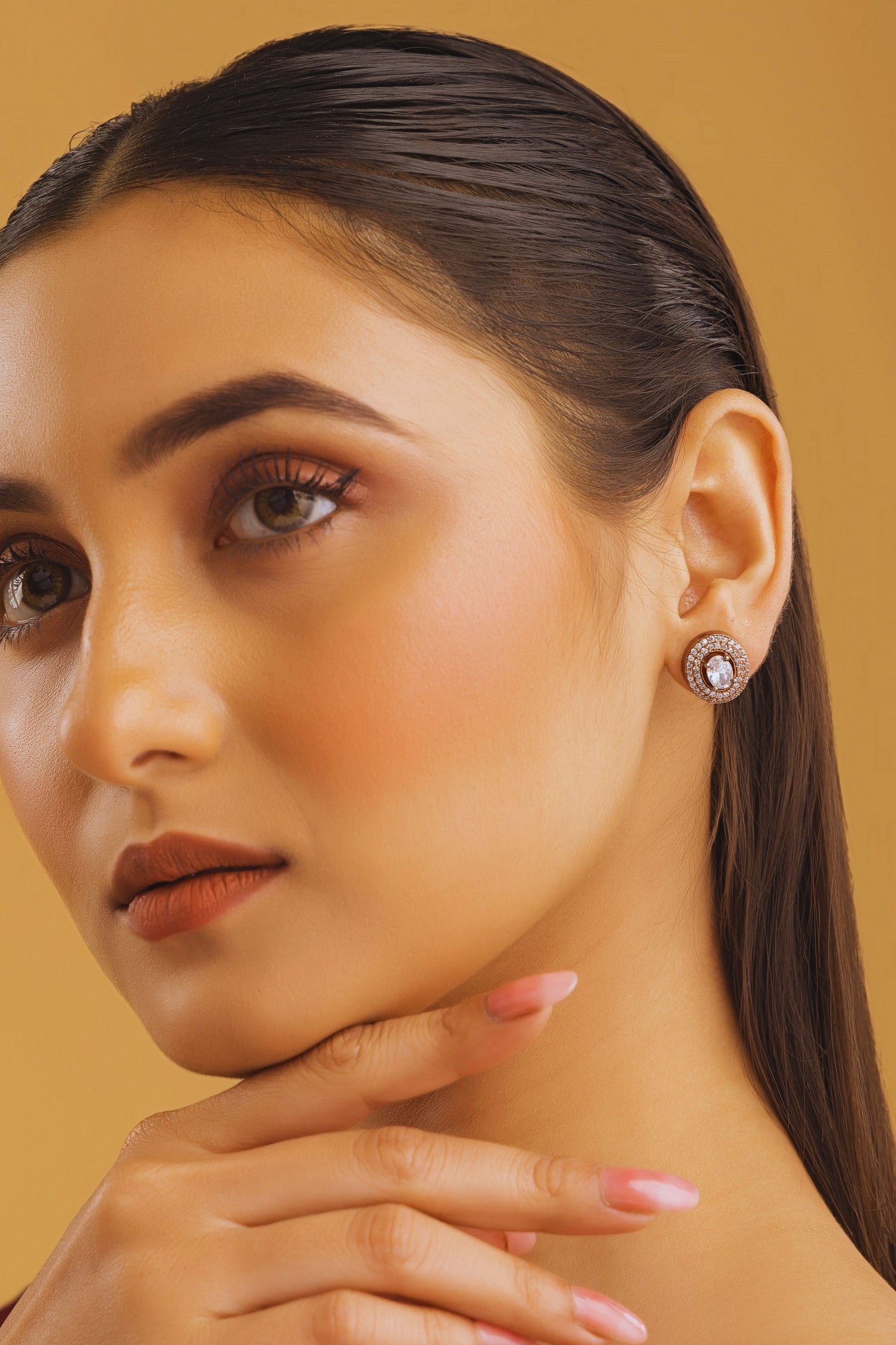 Close-up of a woman wearing an earring with a beige background