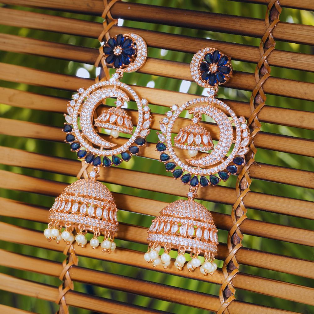 Ornate earrings with blue and gold details on a woven surface