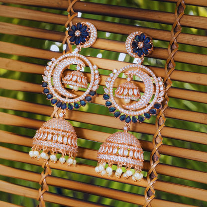 Ornate earrings with blue and gold details on a woven surface