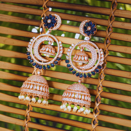 Ornate earrings with blue and gold details on a woven surface