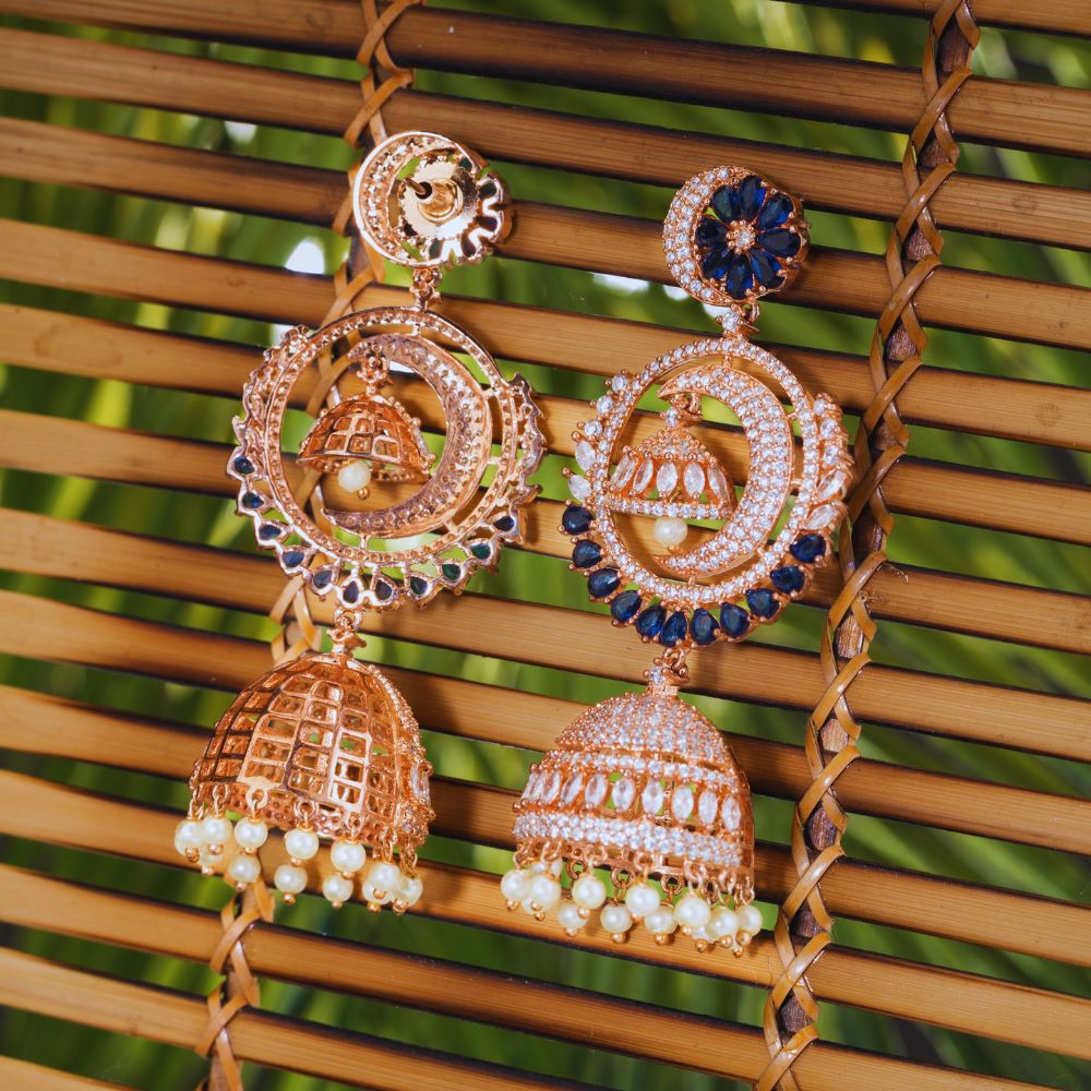 Ornate gold earrings with blue and pearl accents on a woven background