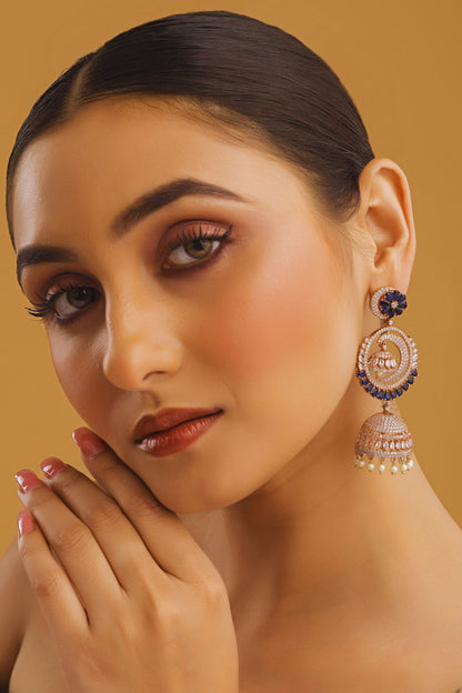 Woman wearing large, ornate earrings against a warm background