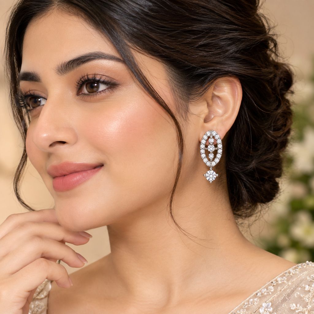 A close-up lifestyle shot of a woman wearing a sparkling oval drop earring with clear stones. The earring features a double-row oval setting with a dangling floral accent.