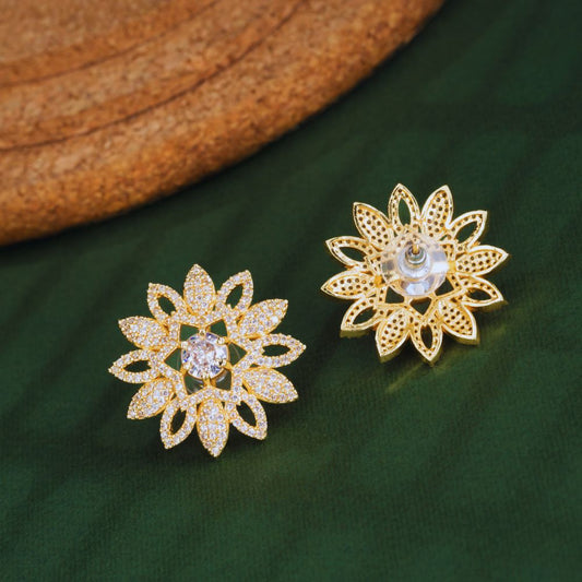 Gold floral earrings with clear stones on a green fabric background