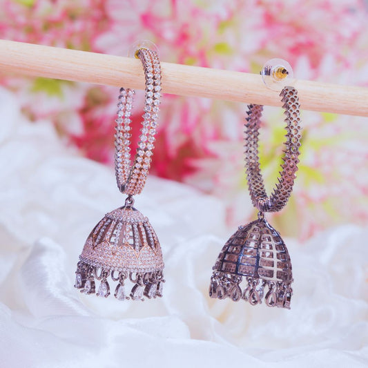 Pair of silver jhumka earrings on a wooden stick with a floral background