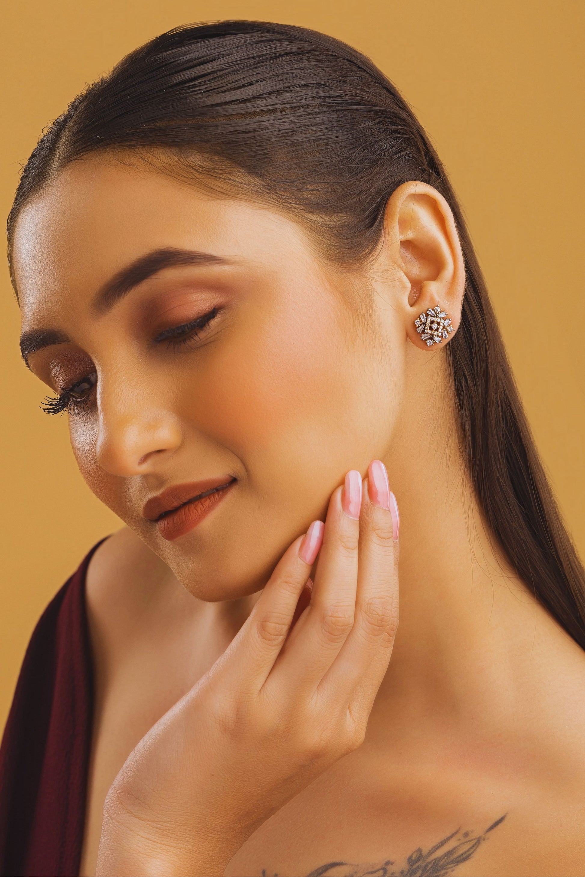 Woman wearing a decorative earring against a beige background