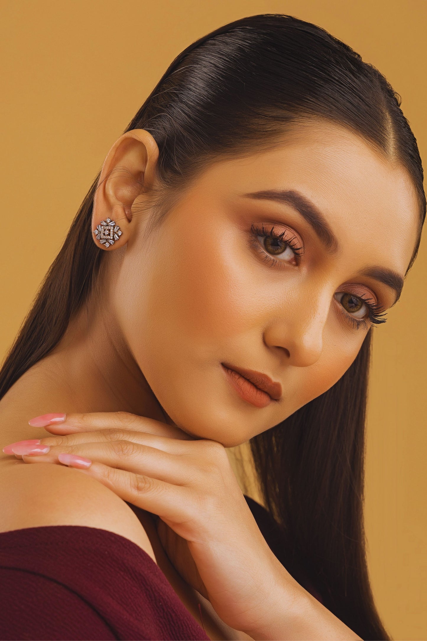 Woman with elegant makeup and jewelry against a beige background