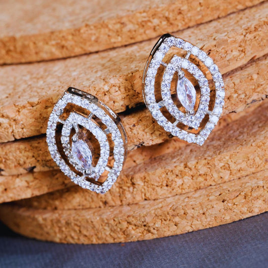 Pair of silver earrings with clear stones on a textured brown surface