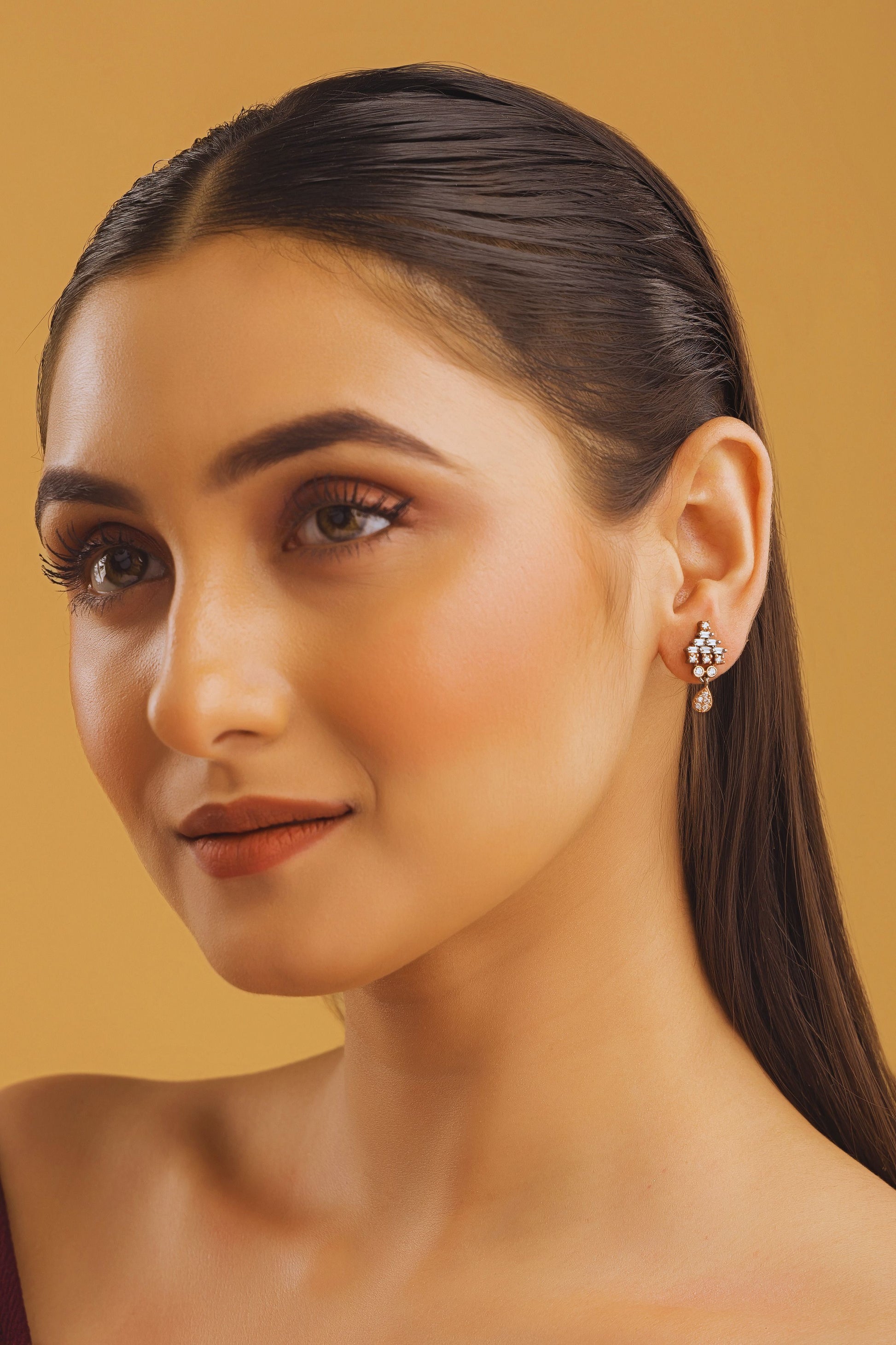 Woman with styled hair and earrings against a beige background