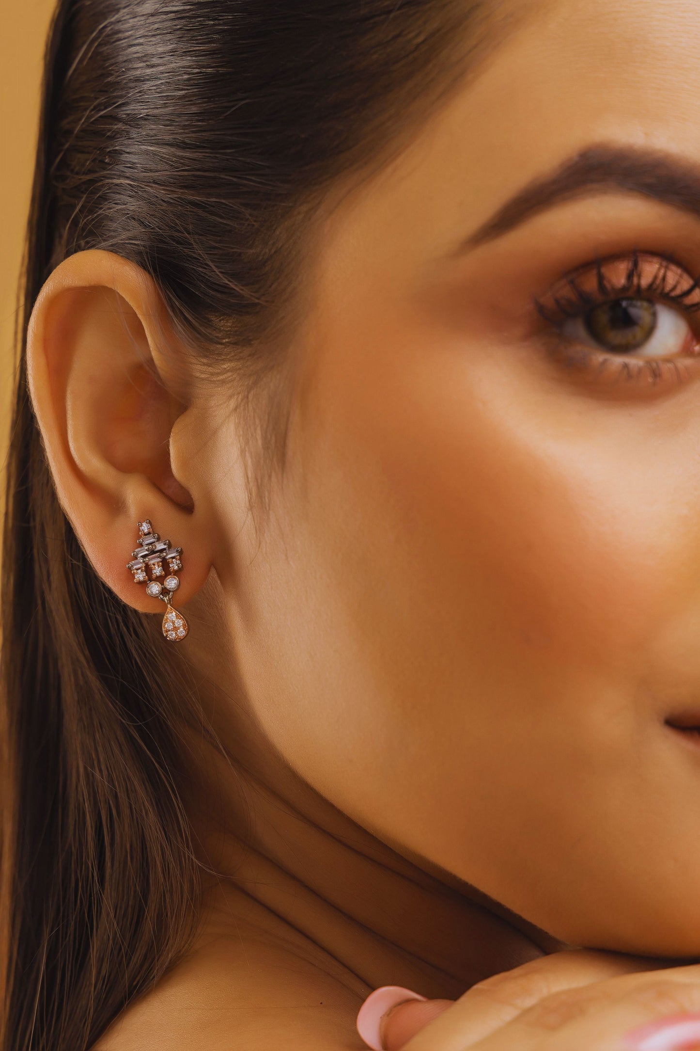 Close-up of a woman's ear with a diamond earring on a beige background