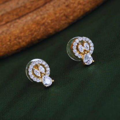 Gold and diamond earrings on a dark green surface