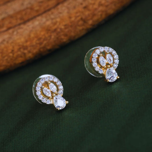 Gold and diamond earrings on a dark green surface