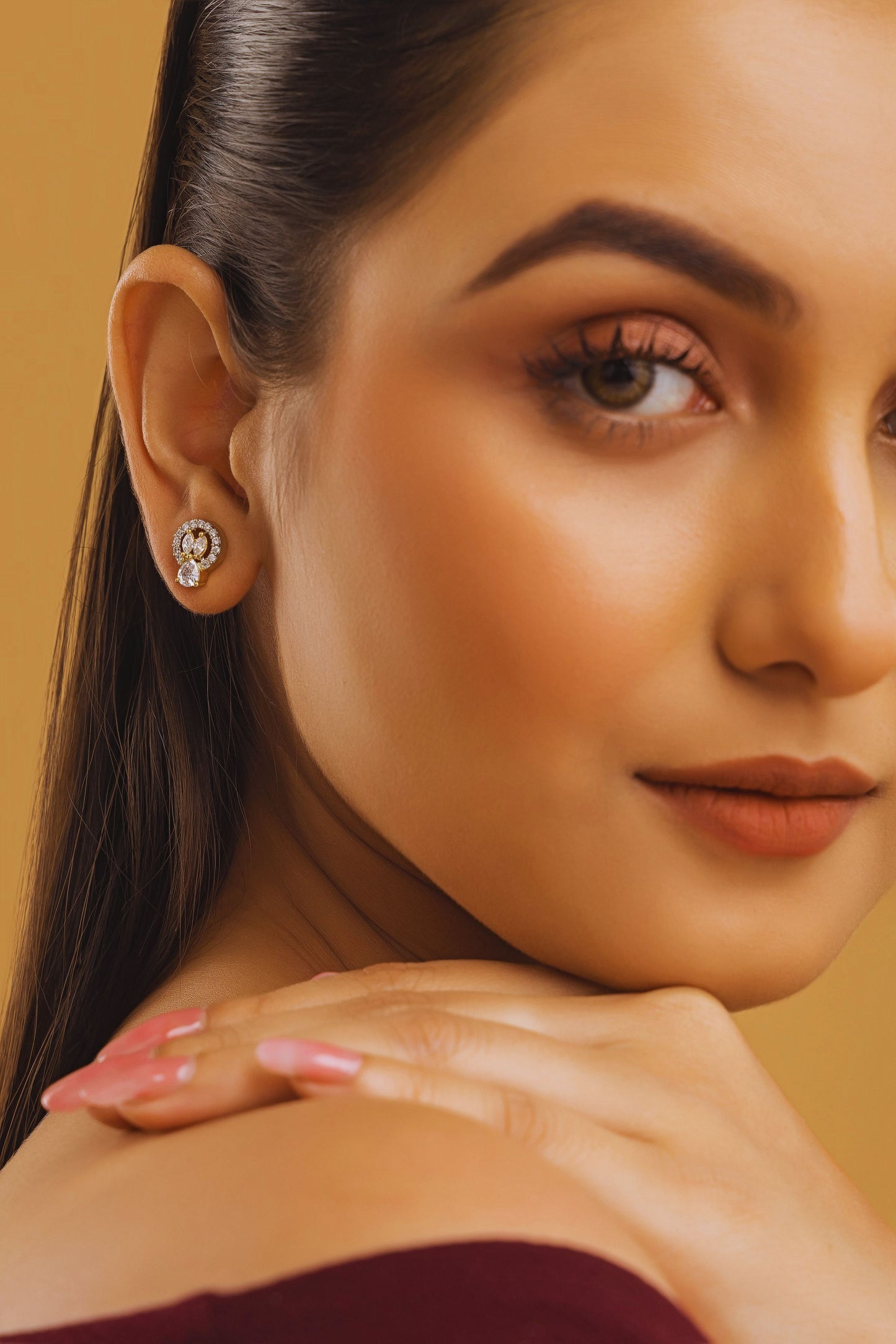 Close-up of a woman wearing an earring with a yellow background