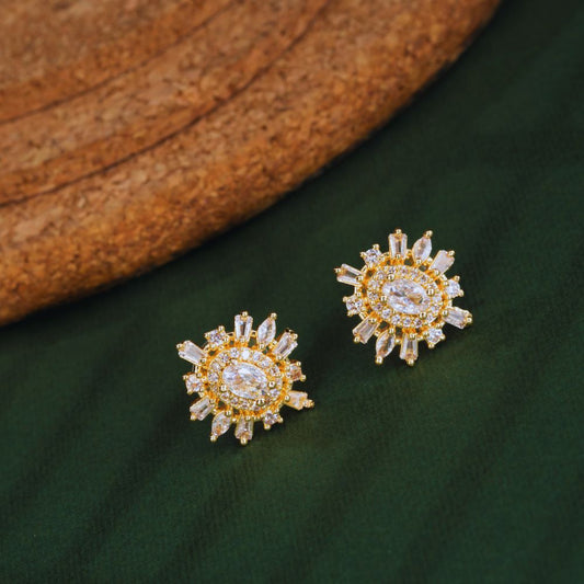 Gold and diamond earrings on a green fabric background