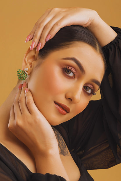 Woman wearing a green earring against a beige background