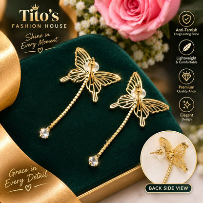 A pair of gold butterfly dangle earrings displayed on a dark green velvet jewelry box, with a pink rose and ribbon in the background. The image includes promotional text and feature icons from Tito's Fashion House, plus a circular inset showing the back side of the earrings.