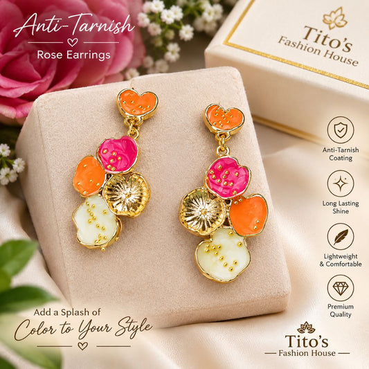 A pair of colorful rose-shaped drop earrings displayed on a beige jewelry box. The earrings feature gold-plated metal frames with orange, pink, and white enamel flower petals, some with gold glitter details.