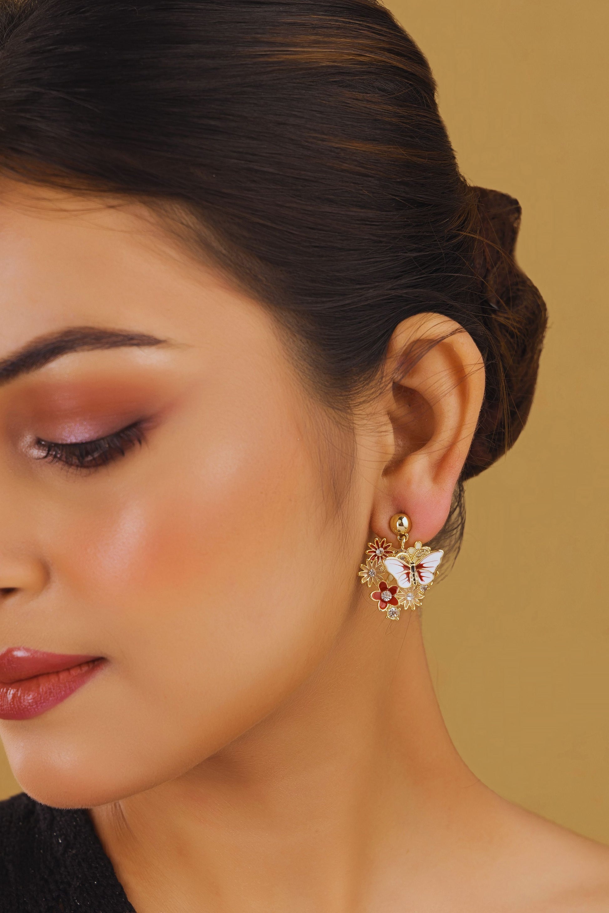 Close-up of a woman wearing a decorative earring against a beige background