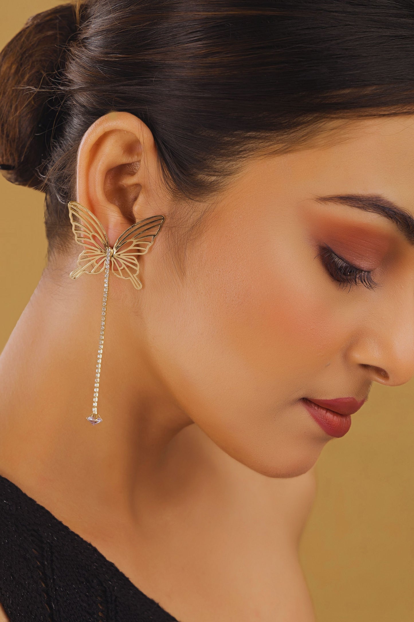 Close-up of a woman wearing a butterfly-shaped earring with a blurred background