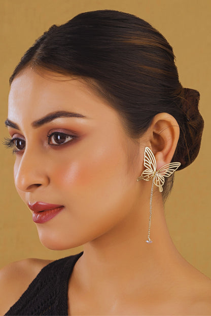 Woman wearing a butterfly-shaped earring against a beige background
