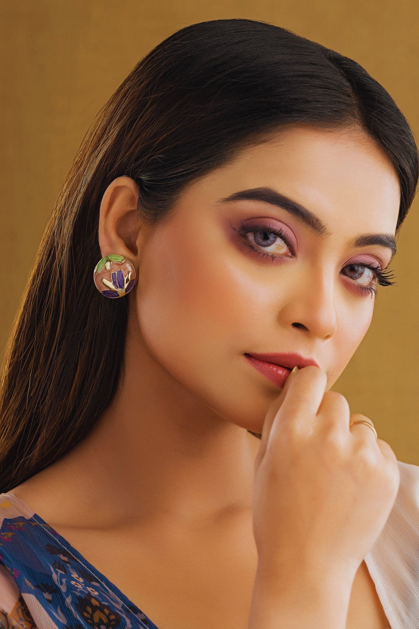 Woman wearing earrings with a gold background