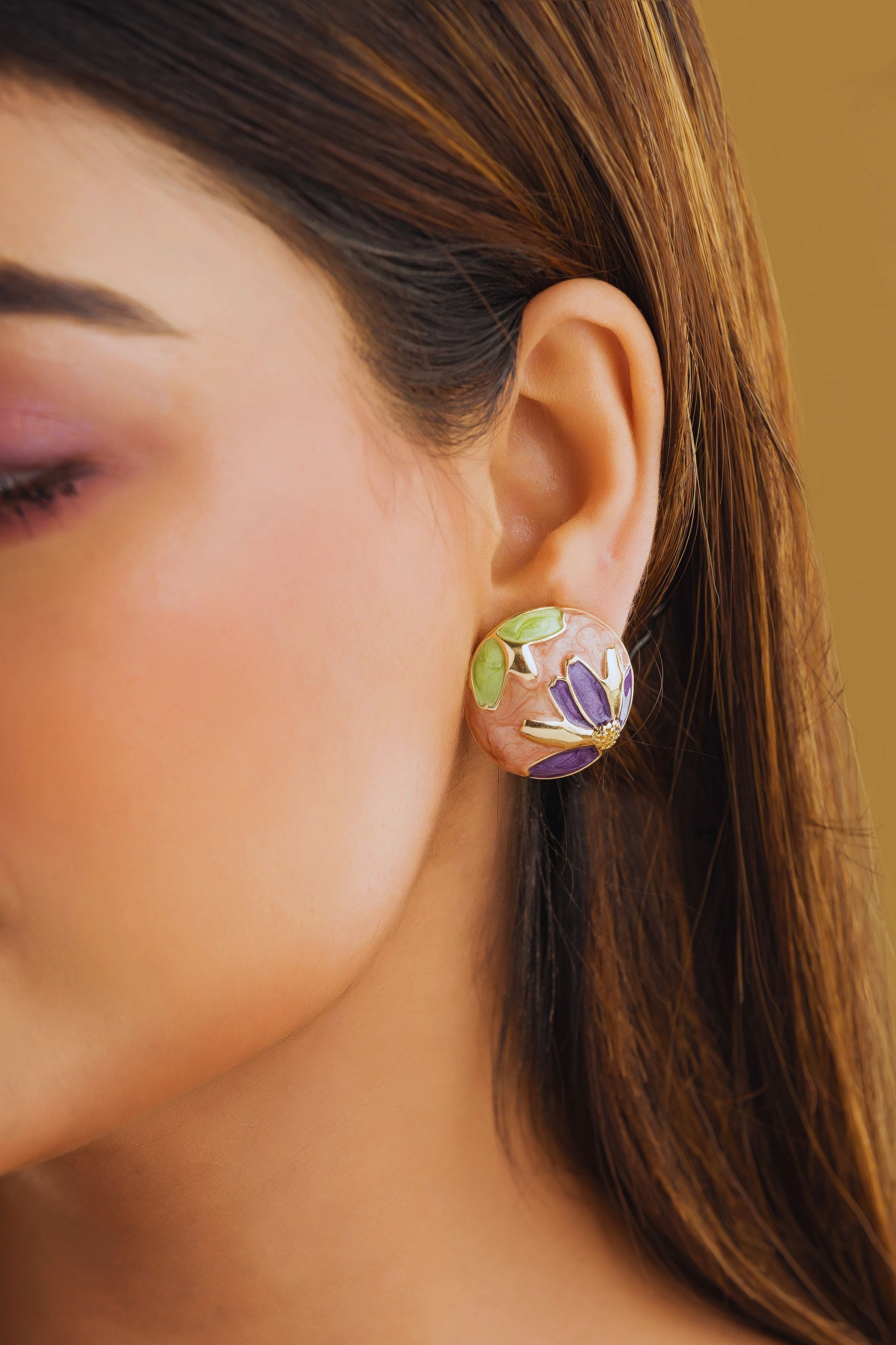 Close-up of a woman's ear wearing a colorful earring against a blurred background