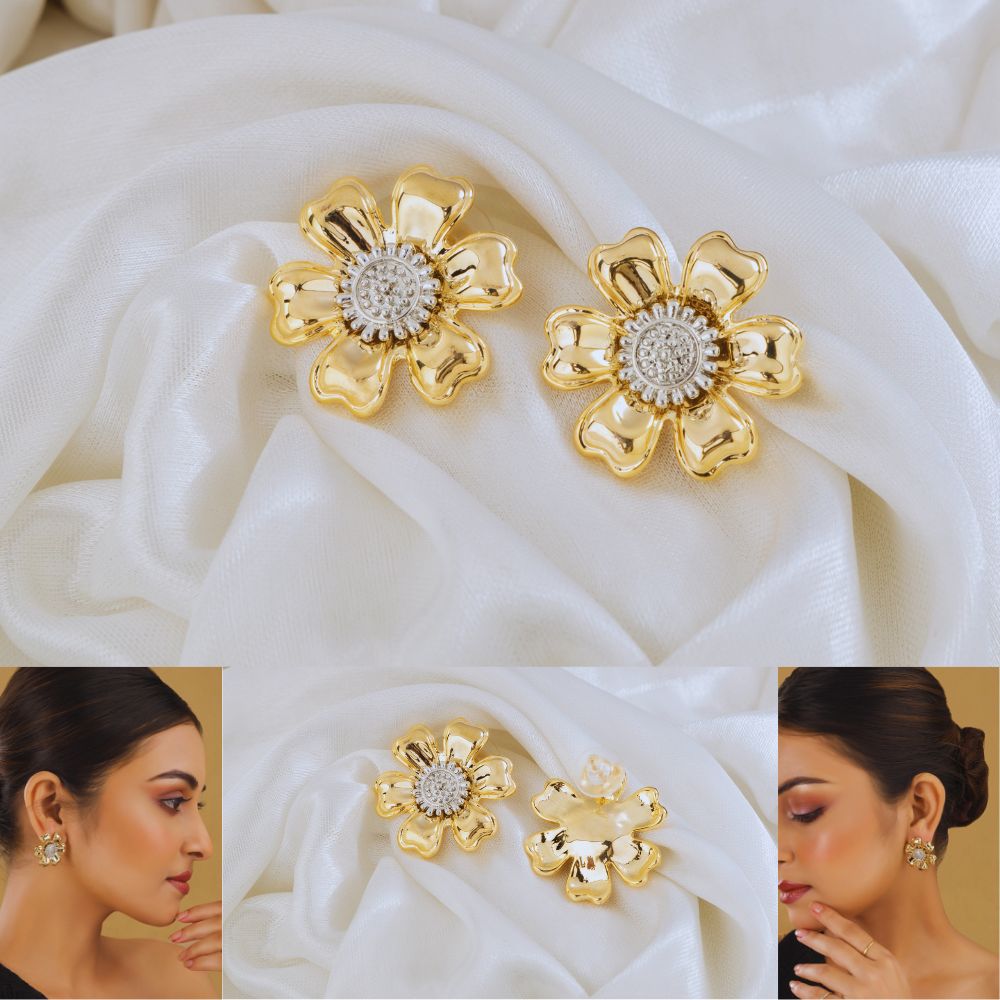 Gold flower-shaped earrings with diamond center on white fabric, shown on a model.