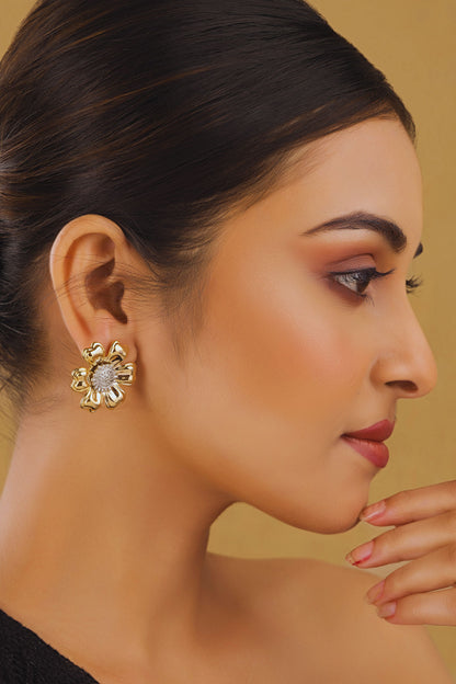 Woman wearing a gold earring with a clear gemstone on a beige background