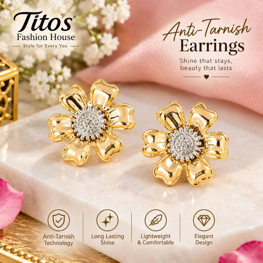 A pair of gold flower-shaped stud earrings with clear crystal centers, displayed on a white marble slab with pink fabric and floral props. The image includes the brand name Titos Fashion House and marketing text for anti-tarnish earrings.