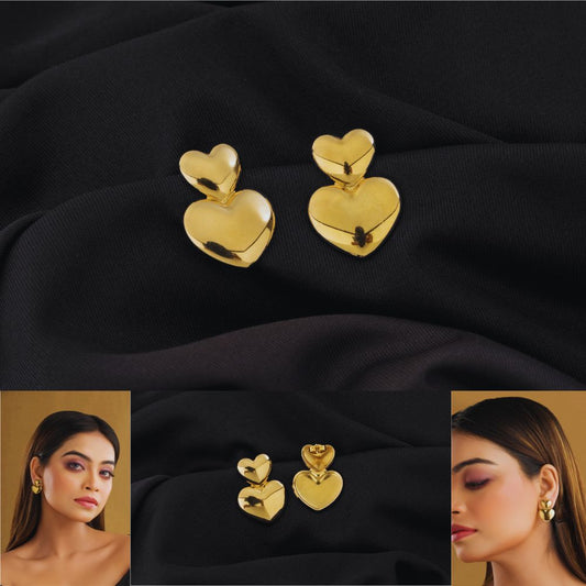 Gold heart-shaped earrings on black fabric with model wearing them.