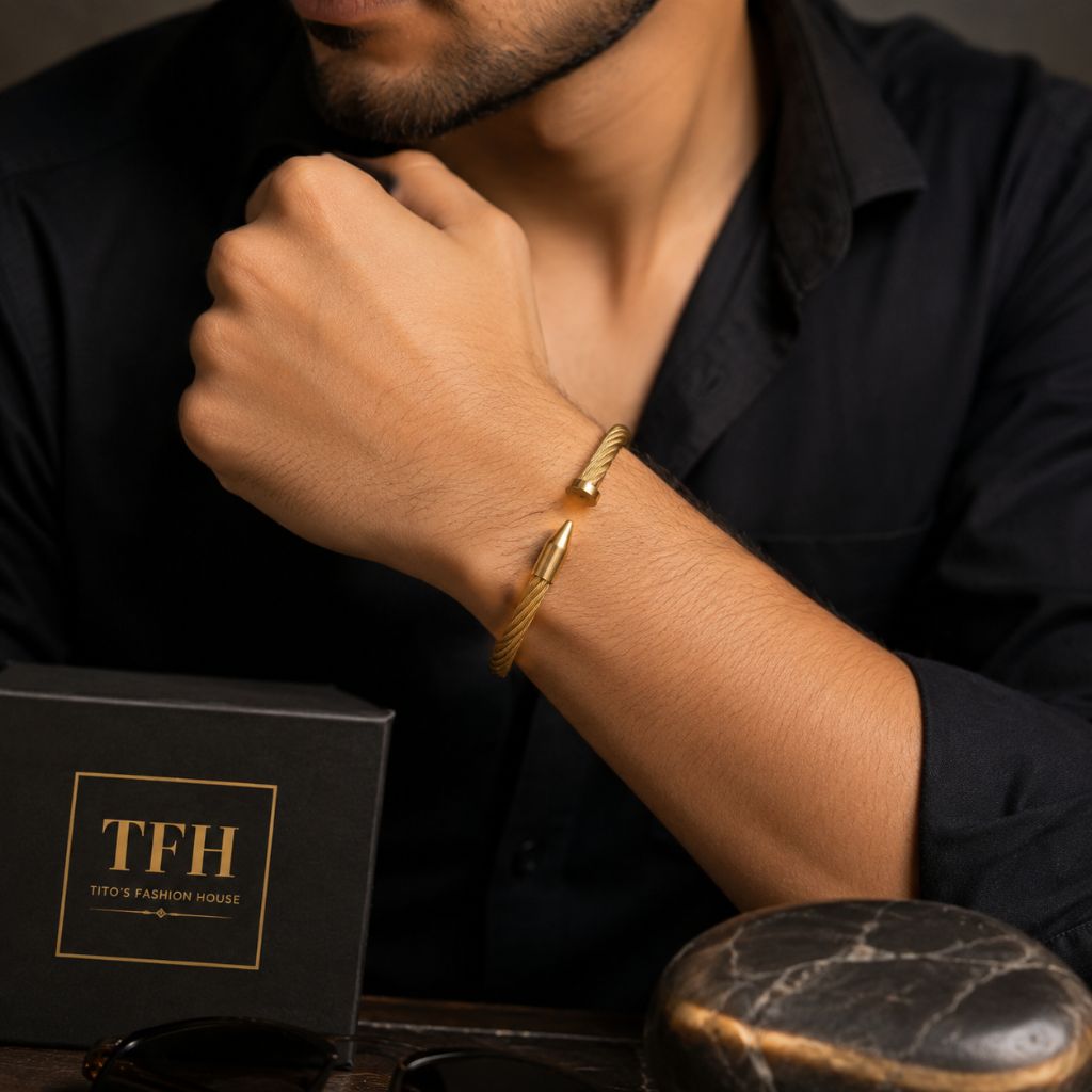 A man wearing a gold-toned twisted wire cuff bracelet with a spearhead detail, shown in a close-up lifestyle shot with a black TFH (Tito's Fashion House) gift box.