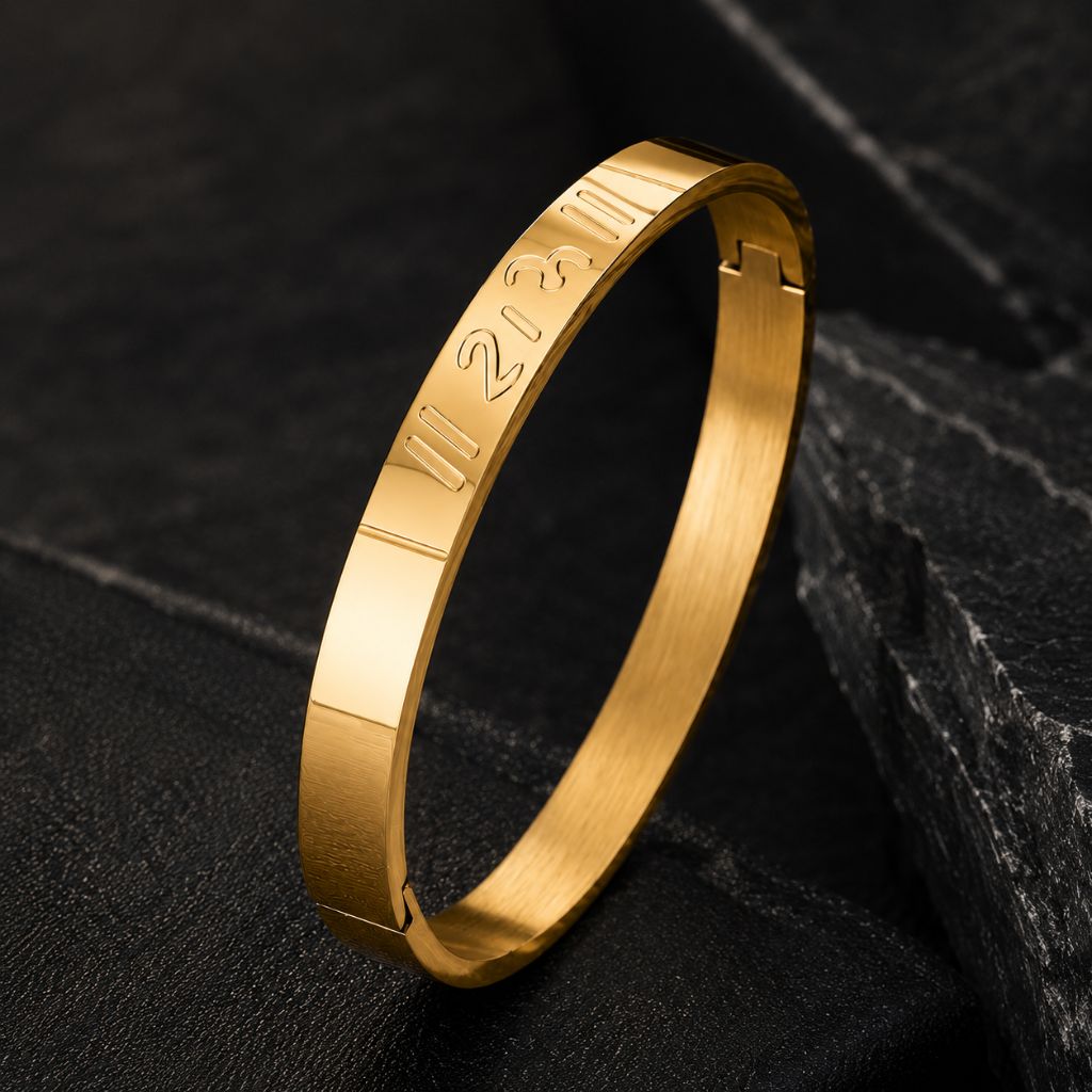 A gold-plated stainless steel bangle bracelet with engraved Roman numerals, displayed on a dark textured slate surface.