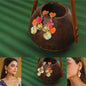 Colorful earrings displayed on a coconut shell with a green background