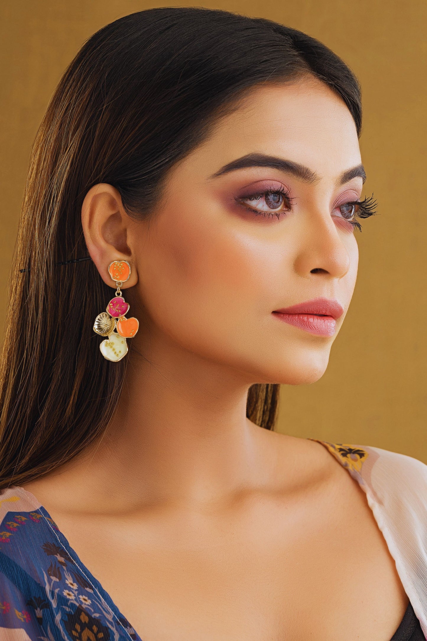 Woman wearing colorful earrings against a gold background