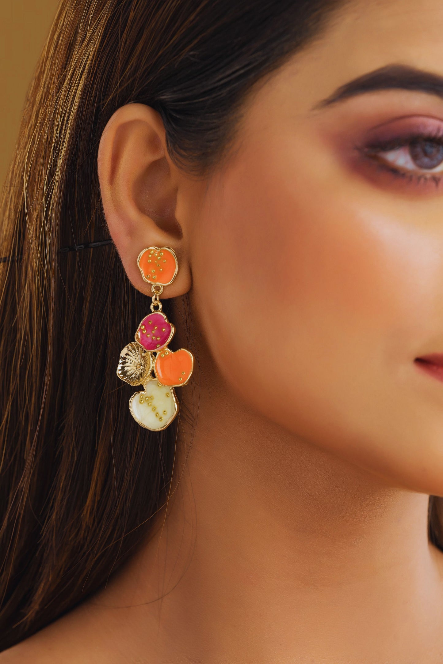 Close-up of a woman wearing colorful earrings with a neutral background