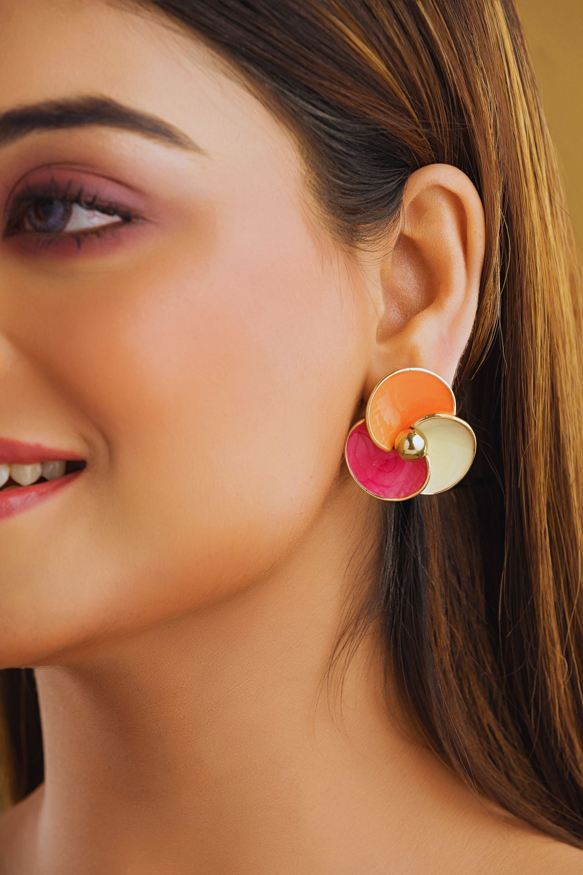 Close-up of a woman wearing colorful earrings with a neutral background