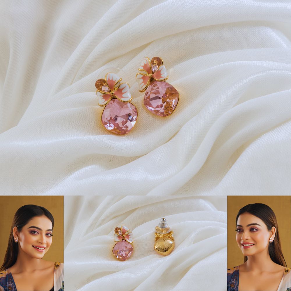 Pink and gold earrings on a white fabric background with a woman wearing them.