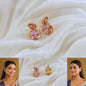 Pink and gold earrings on a white fabric background with a woman wearing them.