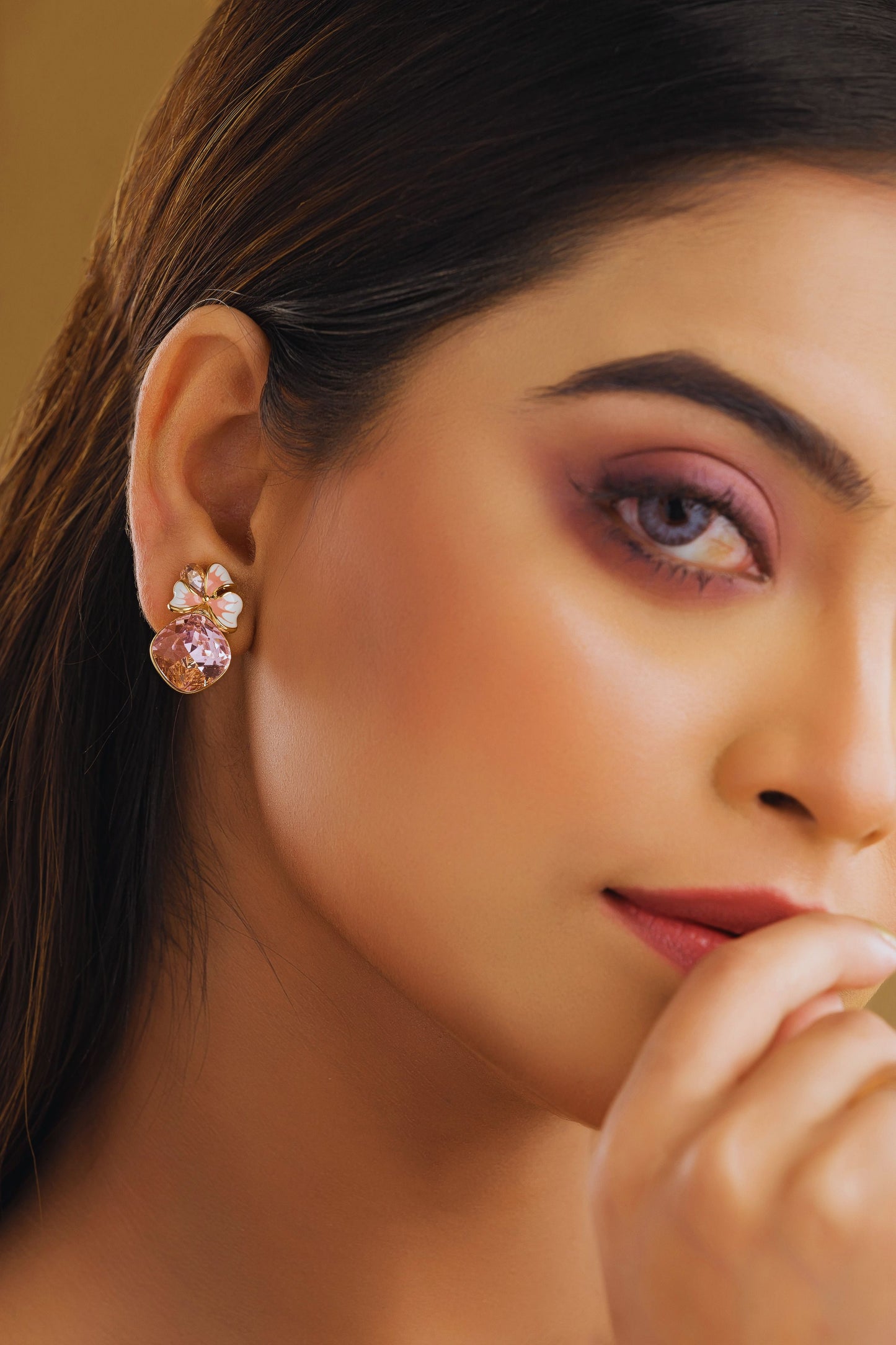 Close-up of a woman wearing a pink floral earring with a blurred background