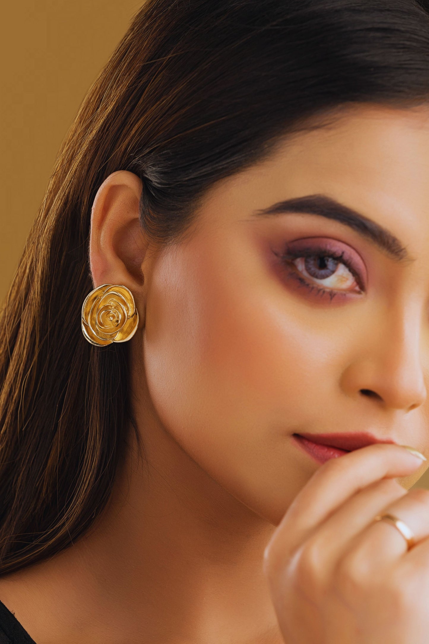 Close-up of a woman wearing gold earrings with a blurred background