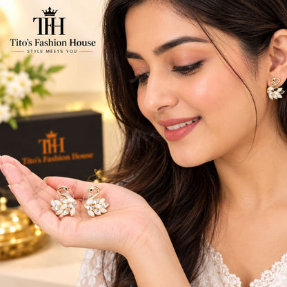 A woman in a white lace top holds a pair of gold and white floral stud earrings in her hand, with the Tito's Fashion House brand logo and box visible in the background.