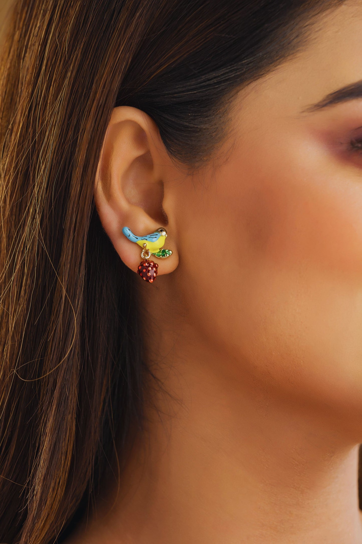 Close-up of a woman's ear wearing colorful earrings with a blurred background