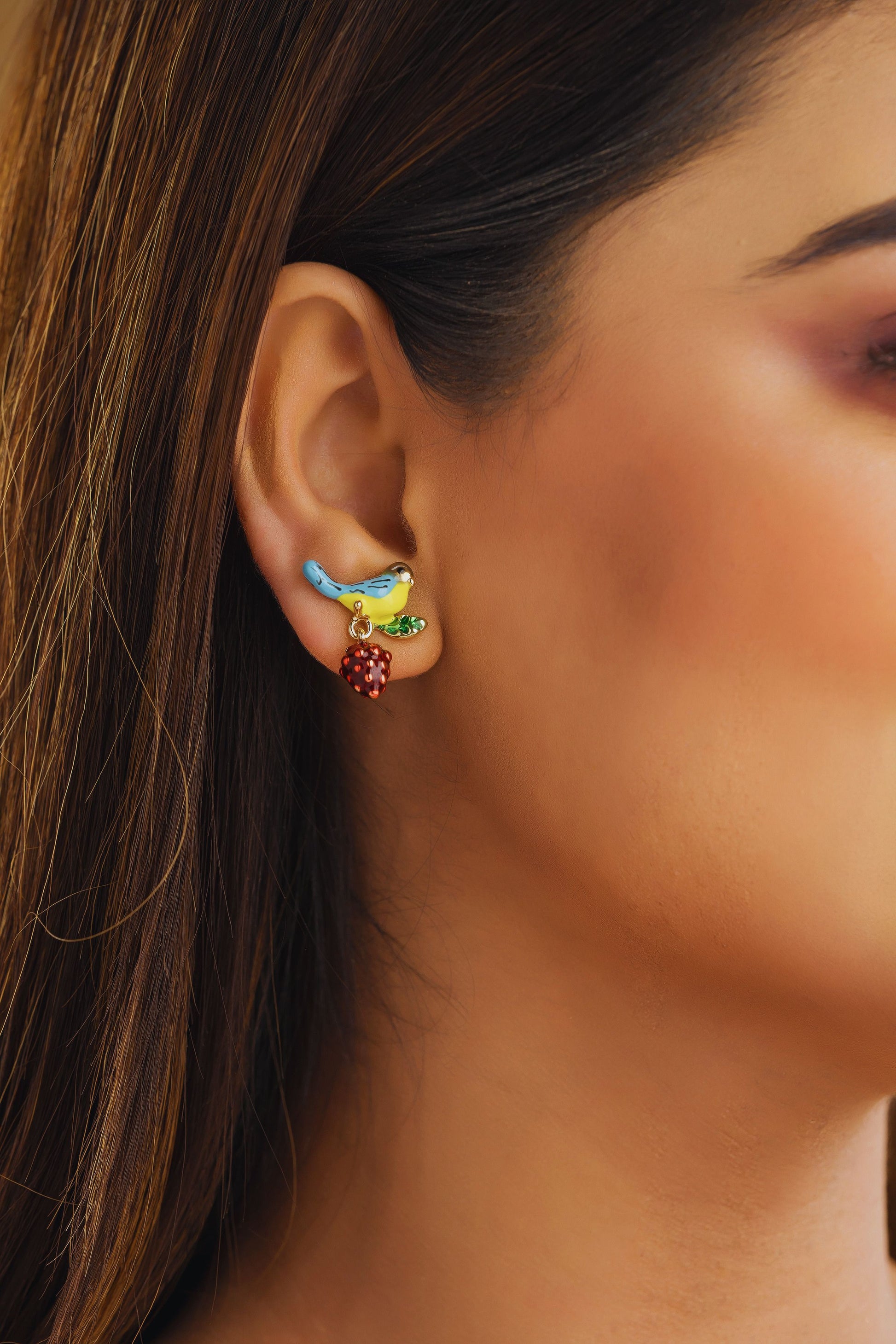 Close-up of a woman's ear wearing colorful earrings with a blurred background